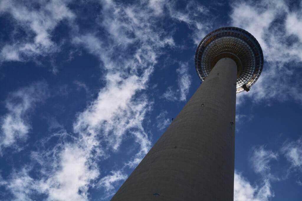 der Fernsehturm von untern gegen den dunkelbauen Himmel mit leichten weißen Wolken