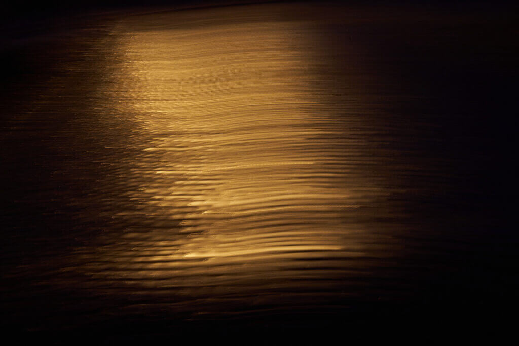 verwischte Reflexe einer Laterne in goldgelb auf Kopfsteinpflaster in der Nacht